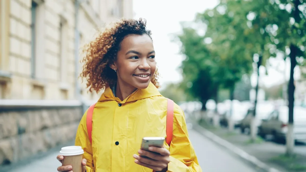 Deux mains autour d'une tasse, un téléphone allumé posé à côté, sur une table en bois éclairée à la bougie