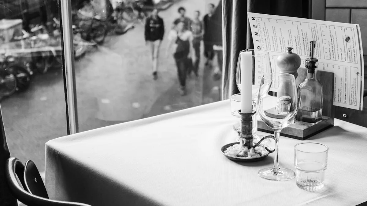 Deux personnes attablées dans un café de jour pour un premier rendez-vous, une conversation calme autour de deux tasses