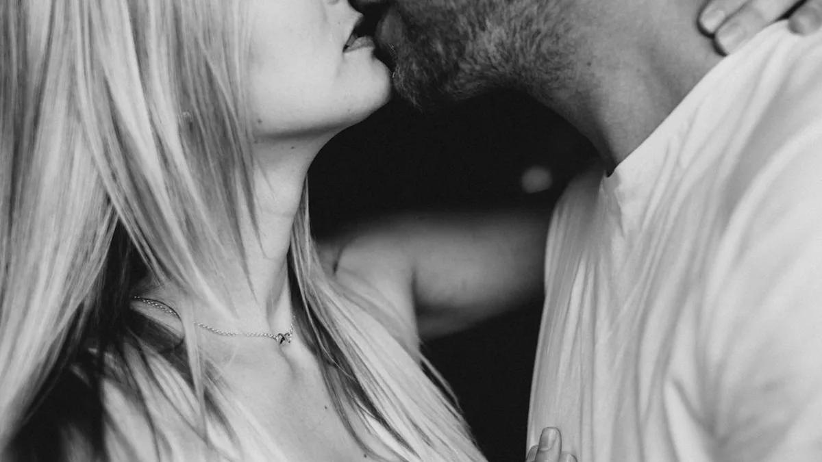 Un homme et une femme s'embrassent, photo en noir et blanc cadrée sur le bas des visages
