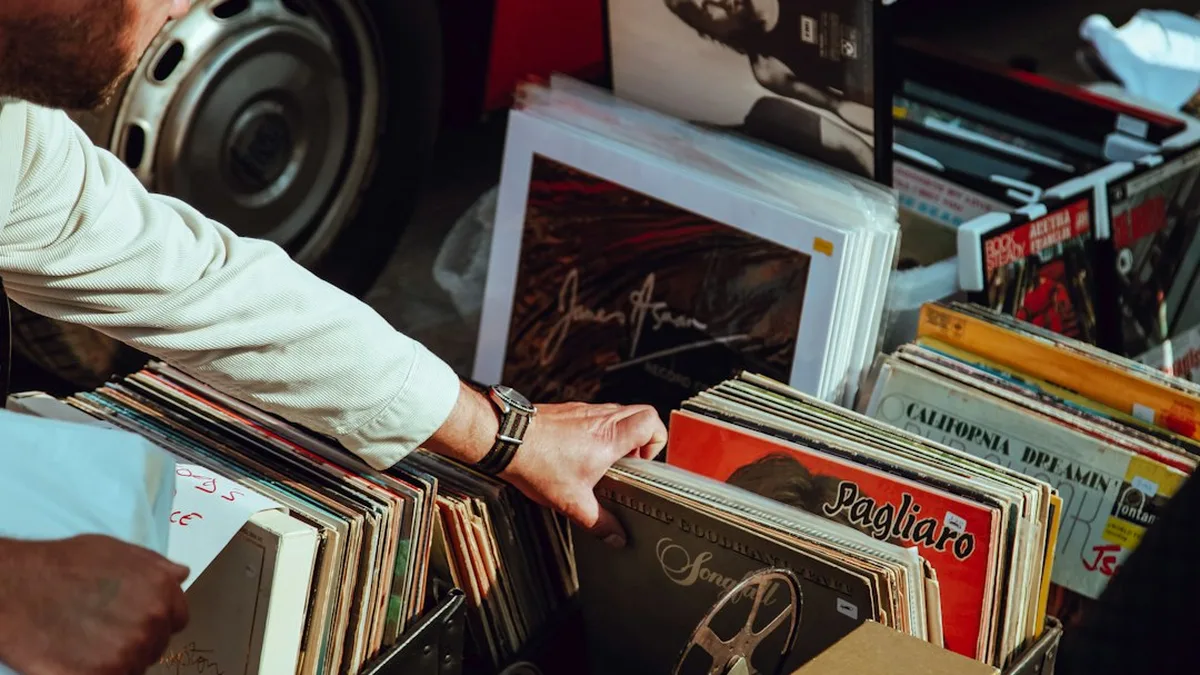Une main fouille dans des bacs de disques vinyles sur un marché aux puces